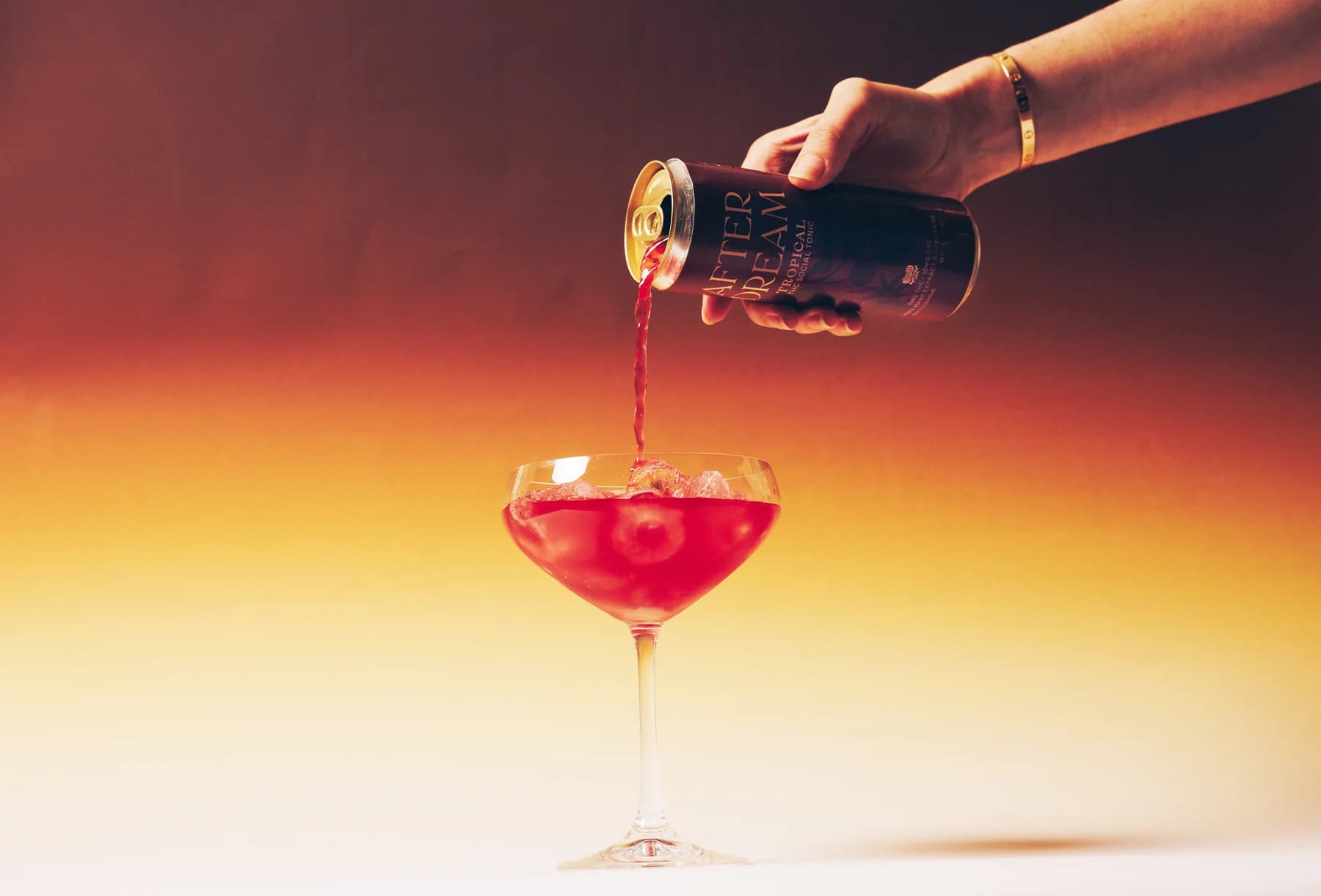A can of Afterdream Tropical THC social tonic being poured into a coupe glass