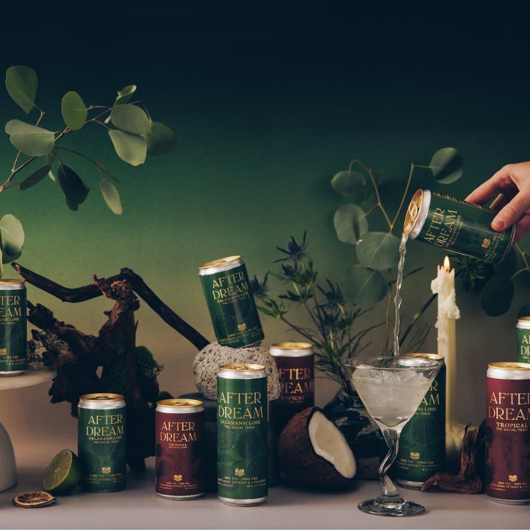 Bottles of Afterdream Tropical and Calamansi Lime THC social tonic styled with candles and a cocktail